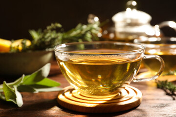 Cup of aromatic herbal tea on wooden table, closeup