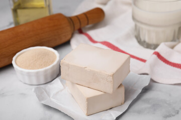 Granulated and compressed yeast on white marble table, closeup
