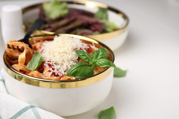 Delicious pasta with tomato sauce, basil and parmesan cheese on white table, closeup. Space for text