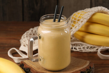 Mason jar with banana smoothie on wooden table