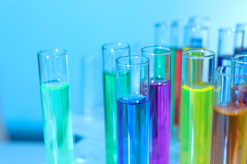 Many test tubes with colorful liquids on blurred background, closeup