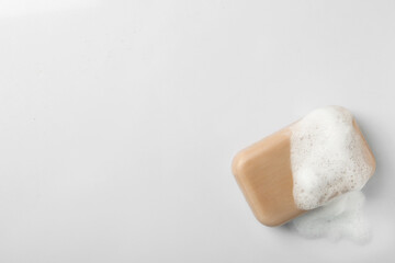 Soap with fluffy foam on white background, top view