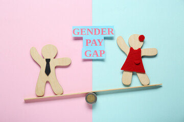 Gender pay gap. Wooden figures of man and woman on miniature seesaw against color background, flat...