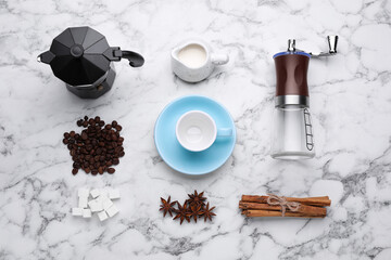 Flat lay composition with manual coffee grinder and beans on white marble table