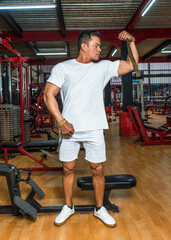 Fototapeta na wymiar A gym athlete wearing a white blank shirt doing a pose at a gym