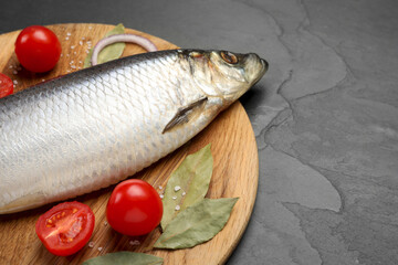 Tray with salted herring, onion, bay leaves and cherry tomatoes on black table, closeup. Space for text