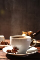 Cup of aromatic hot coffee with anise stars on wooden table