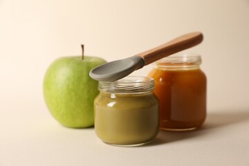 Healthy baby food, apple and spoon on beige background