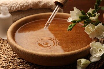 Dripping essential oil into bowl on table. Aromatherapy treatment