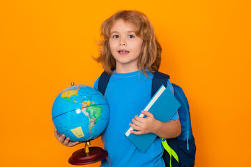 Fototapeta premium Smart child, clever school kid. School boy hold world globe and book, isolated on yellow studio background. School and kids. Cute blonde child with a book learning. Knowledge day.