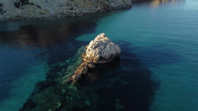 Aerial drone orbiting around white rock formation in South Sardinia at sunset