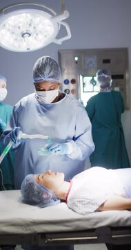 Vertical video of diverse surgeons with face masks during surgery