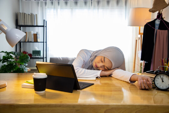 Muslim businesswoman clearing sales target and sleep less on table at working space. Asian woman in hijab failing to meet deadline, having difficulty with business project.