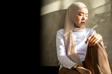 Muslim girl in hijab sit alone under table get bad news feel depressed and frustrated muslim woman suffering from illness worried about unresolved problems feeling sorrow grief hard. Light and shadow