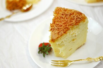 Slice of delicious cheese spongecake isolated on white.