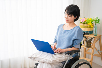 車椅子でノートパソコンを使う若い女性　多様性社会イメージ	