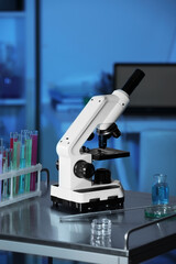Modern microscope with glass slide on metal table in laboratory, toned in blue