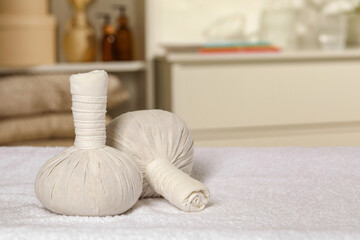 Fototapeta na wymiar Herbal massage bags on bath towel indoors, space for text. Spa procedure