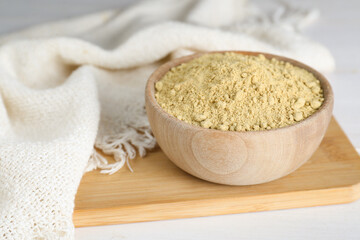 Bowl of aromatic mustard powder on white wooden table, closeup. Space for text