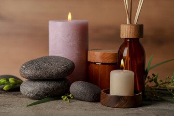 Fototapeta na wymiar Beautiful spa composition with different care products and burning candles on wooden table, closeup