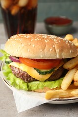 Delicious burger, soda drink and french fries served on grey table, closeup