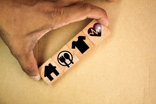wooden cube with icons of food, clothing, housing, medicine, four basic human needs concepts. Four Basic Human Material Needs.