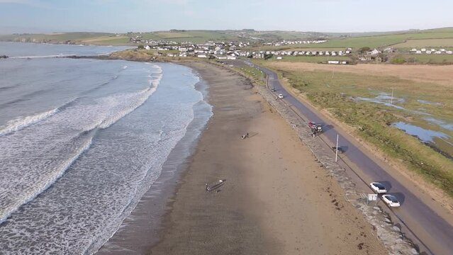 Coastal road, sandy beach and slow motion moving waves in Winter. Irish beach from above.