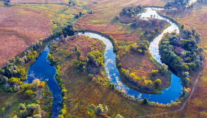 The channel and bends of the river, on a marshy meadow. Orange dry grass, scorched by the summer...