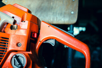 Orange chainsaw close-up. Gasoline tool controls, off button and gas pedal. Filler neck of the tank...