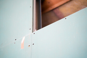 Moisture-resistant drywall is screwed with black self-tapping screws into a metal profile frame...