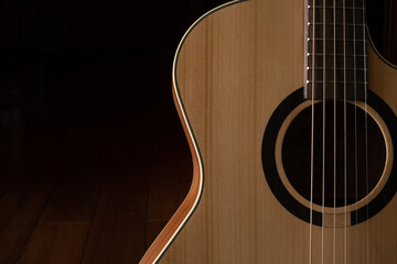 Obraz premium Classic Acoustic guitar close up, dramatically lit on a black background with copy space