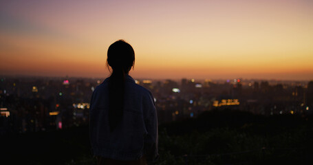 Fototapeta premium Silhouette of woman look at the city under sunset