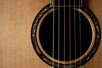 Obraz premium Classic Acoustic guitar close up, dramatically lit on a black background with copy space