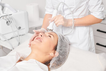 Beautician makes ultrasound skin tightening for rejuvenation woman face using phonophoresis, anti...
