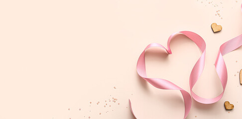 Heart made of pink ribbon on beige background with space for text. Valentine's Day celebration