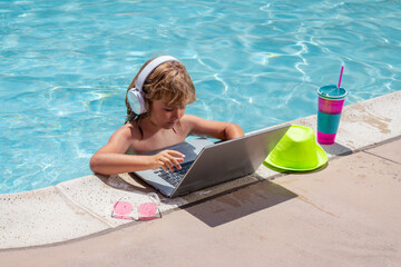 Child with laptop in swimming pool in summer day. Work outside concept, Business and summer.