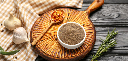 Black pepper powder with garlic and rosemary on dark wooden background