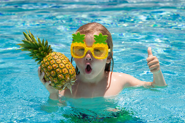 Funny little boy relaxing in a swimming pool, having fun during summer vacation in a tropical resort.