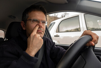 Man in car with finger into nose while driving.