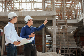 Construction engineer inspecting and working outdoors structure building site with blueprints.