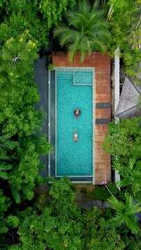 couple in pool, aerial drone view of a swimming pool in the jungle of Krabi Thailand, aerial view with a drone above swimming pool in the jungle of Thailand. a couple of men and women in pool 