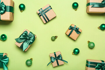 Composition with different gift boxes and Christmas balls on green background