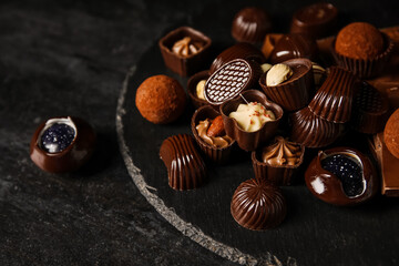 Board with chocolate candies on dark table