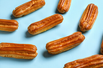 Many sweet eclairs on color background