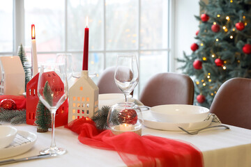 Christmas table setting with candle holders and fir trees in dining room