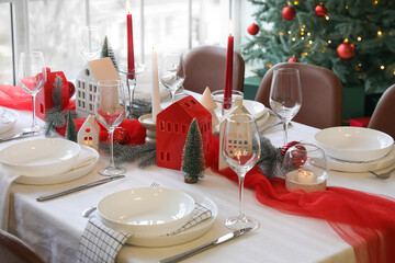 Christmas table setting with candle holders and fir branches in dining room