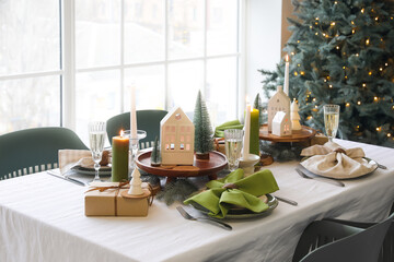 Christmas table setting with candle holders, presents and fir trees in dining room