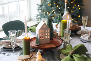 Christmas table setting with candle holders, presents and fir trees in dining room