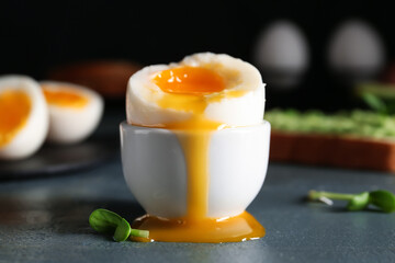 Holder with soft boiled egg on wooden table