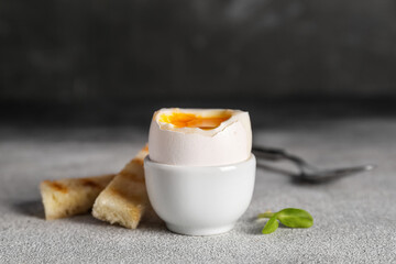 Soft boiled egg with toasted bread on table against black background